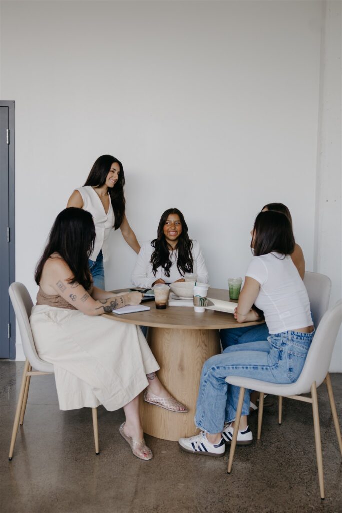 Group of women gathered around a wood table for a meeting, brand photography for a coaching business