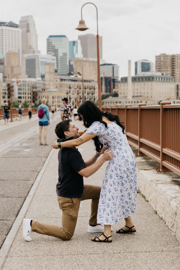 couple hugging closely on the Stone Arch Bridge after their proposal