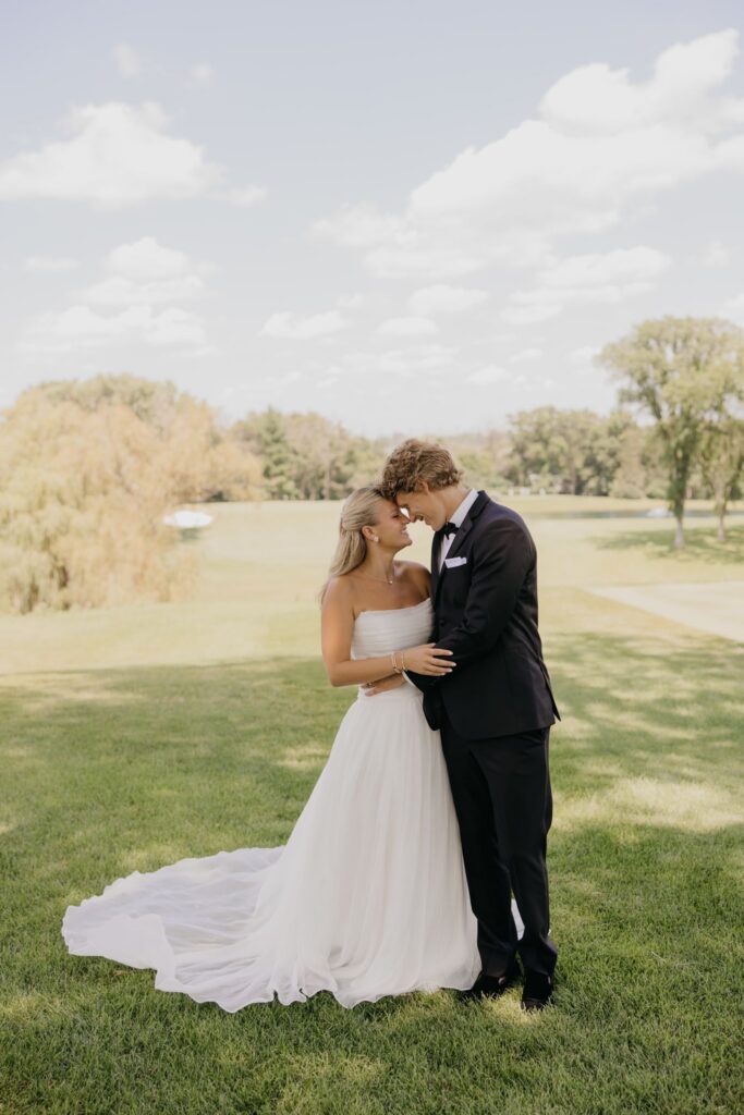 Bride and groom kissing with the golf course fairway stretching behind them