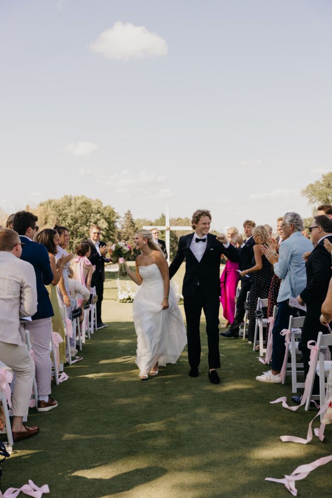 Bride and groom walking hand in hand down the aisle after their ceremony