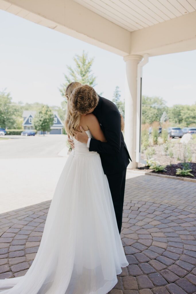 Groom kissing bride under a covered entrance porch at Minneapolis Golf Club