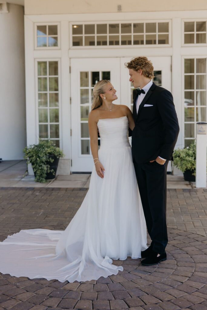 Bride and groom standing together outside the clubhouse entrance