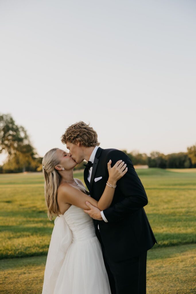 Bride and groom kissing on the golf course at golden hour