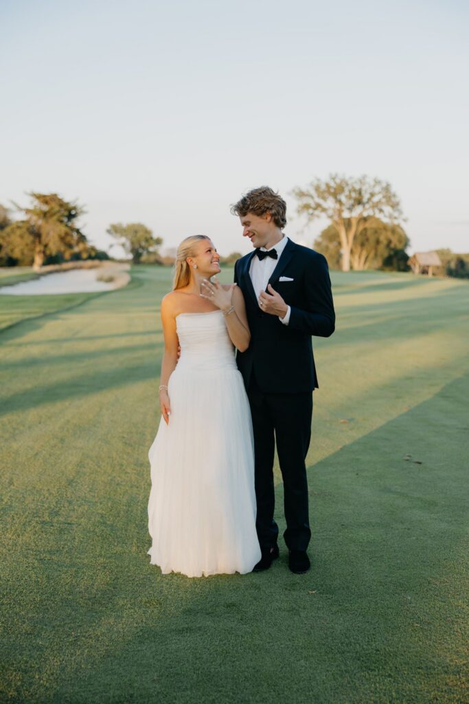 Bride and groom smiling together standing on the fairway