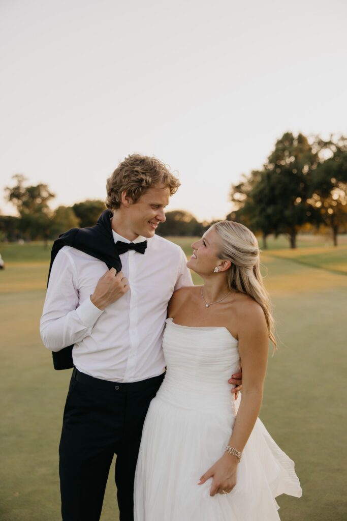 Bride and groom laughing together while walking across the golf course