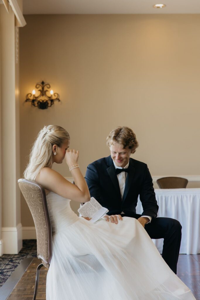 Bride wiping away tears during her first look reaction, seated with groom