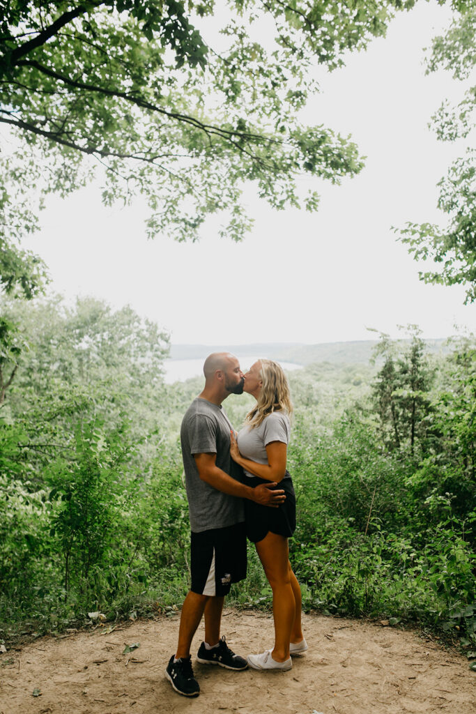 couple kissing on a forest overlook after getting engaged