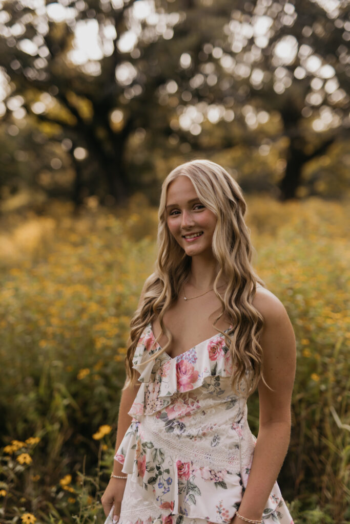 Close-up of senior girl smiling in a wildflower field wearing a floral dress