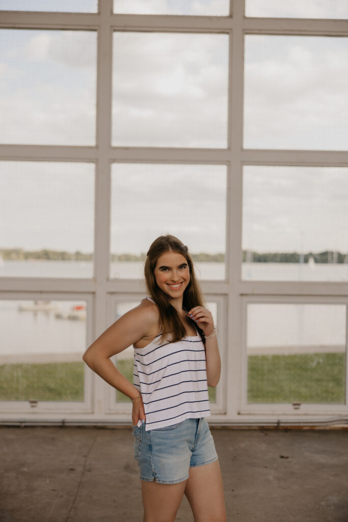 Senior girl posing against a glass railing overlooking the lake