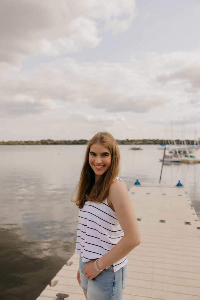 Senior girl in a striped top and shorts standing on a wooden dock by the water