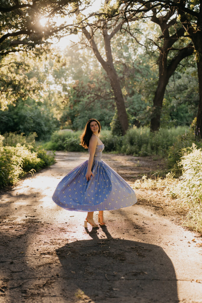 Emma Hollands twirling on a sunlit path in a blue floral dress