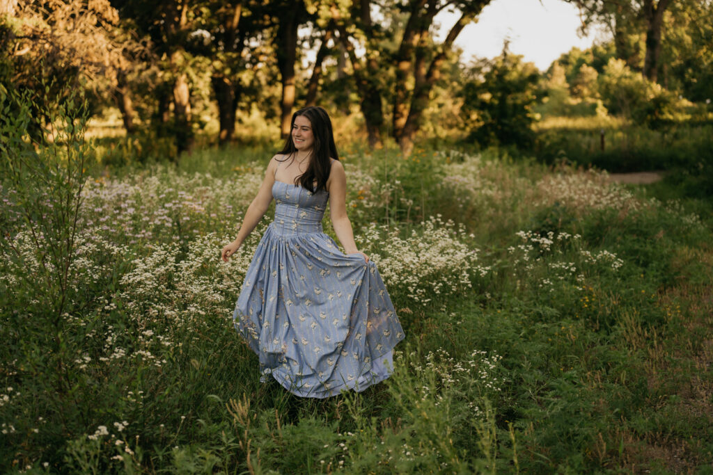 Emma Hollands twirling in a blue floral senior picture dress in a wildflower field