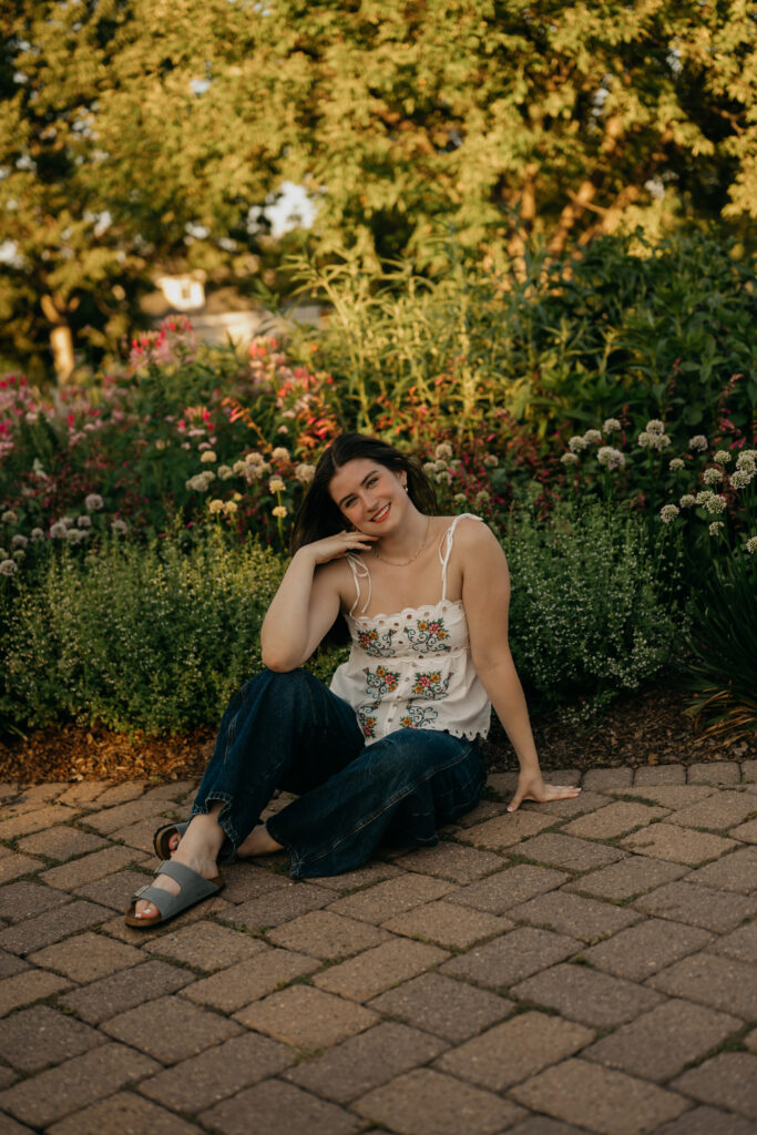 Emma Hollands sitting on a stone path in a white top during her senior session