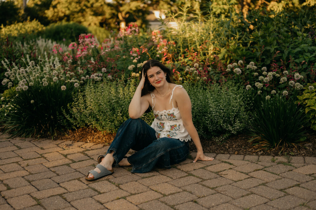 Emma Hollands sitting on a stone path surrounded by garden flowers