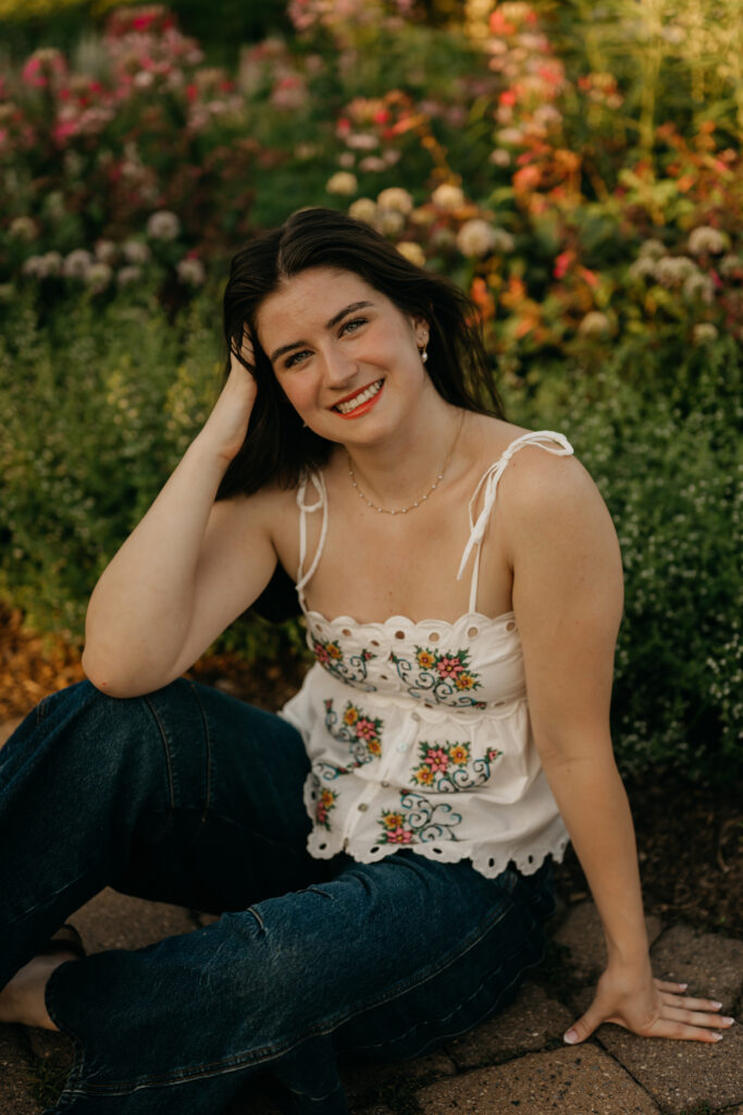Emma Hollands smiling in a white embroidered top surrounded by flowers
