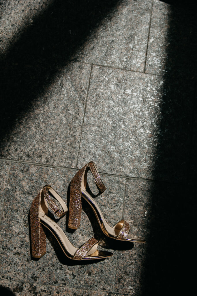 Bride's gold heeled shoes rest on the marble floor in natural light