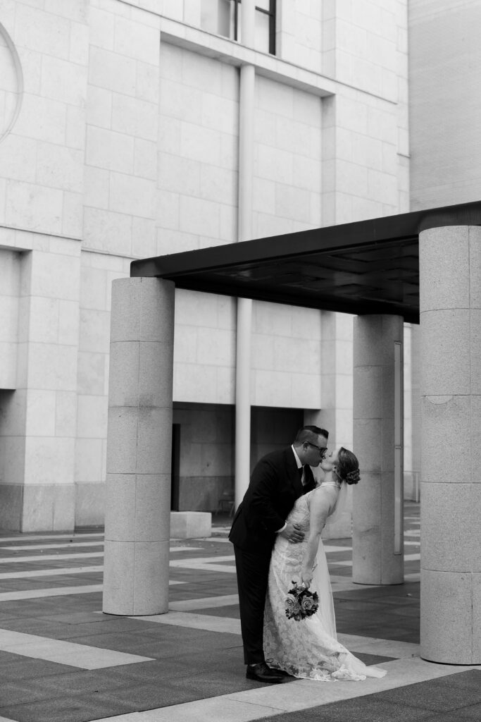 Groom kisses bride's hand under the modern glass entrance canopy at the Minneapolis Institute of Art