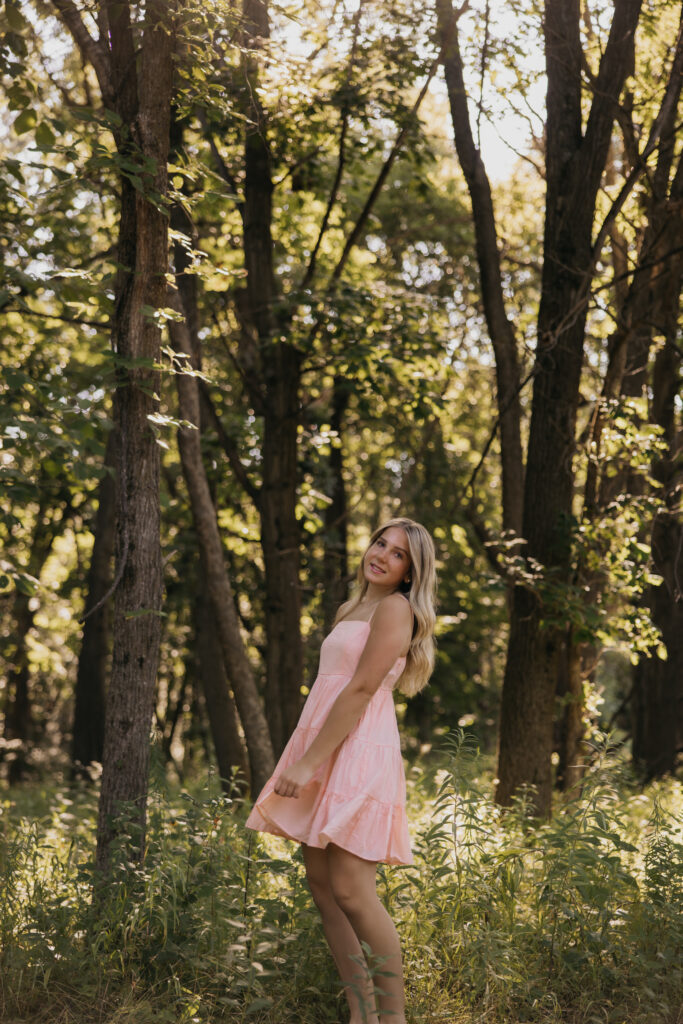 Eve in a pink dress walking through a wooded trail