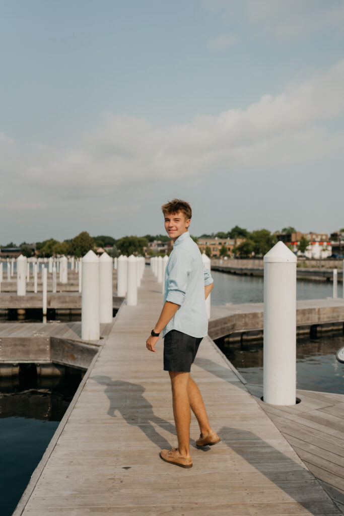 Grant walking down the dock in a light blue shirt, looking back over his shoulder