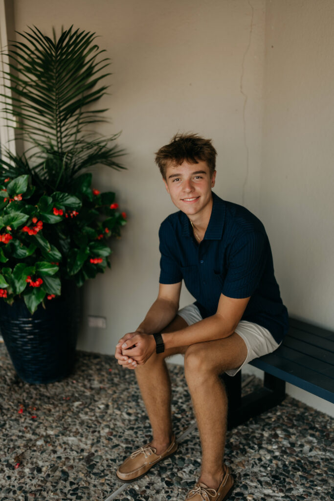 Grant sitting on a bench near potted plants, in a navy shirt