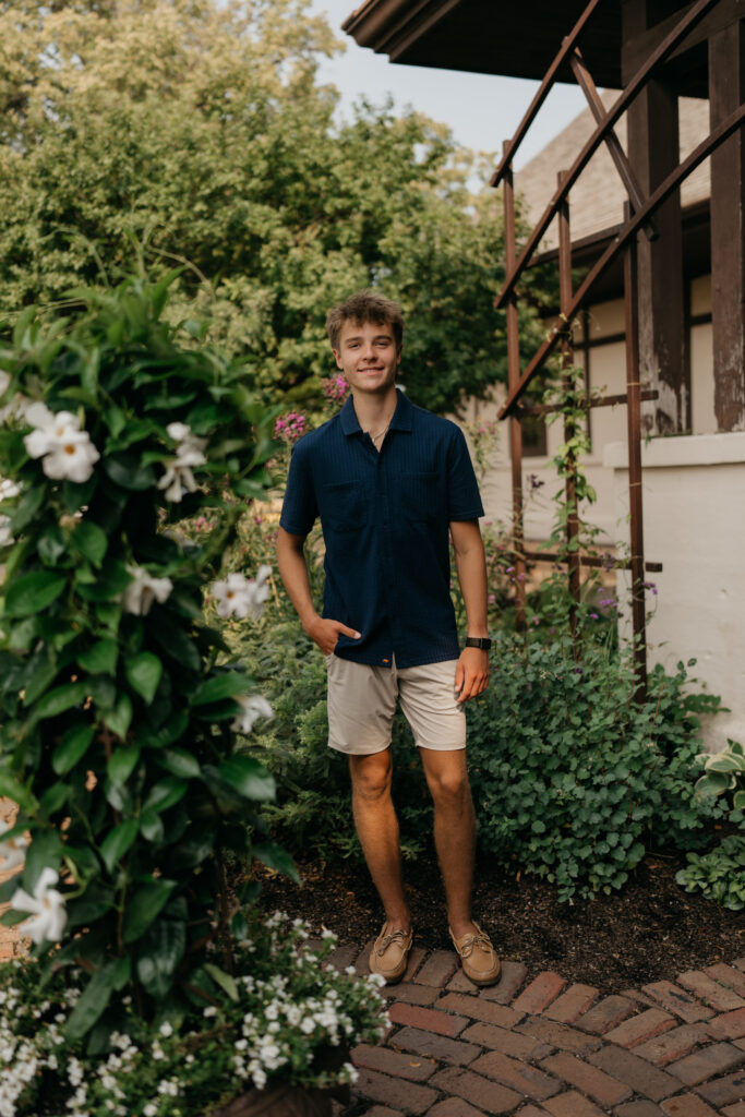 Grant standing among greenery outside a building entrance, in a navy shirt