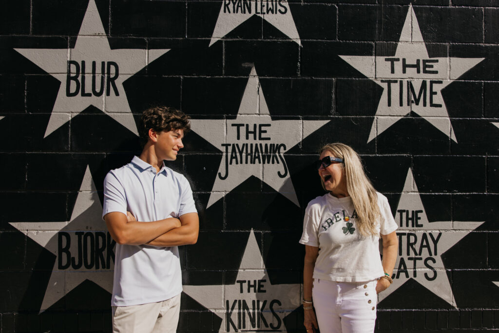 Senior and his mom smiling at each other in front of the black and white music mural