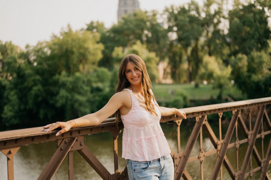 Senior girl leaning on iron bridge railing over the river near St. Anthony Main
