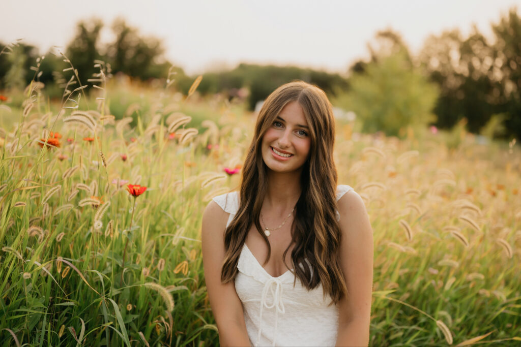 Senior girl in white dress smiling in golden grass field at Pixel Dust Acres