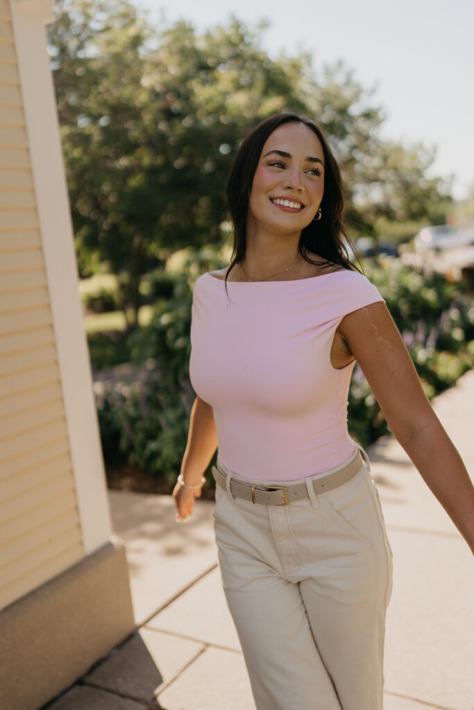 Senior girl in pink top laughing while walking across a garden patio