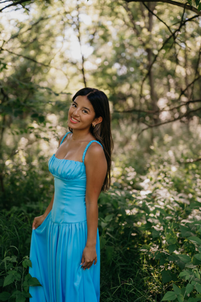 Natalia standing in a blue satin dress in a wildflower field