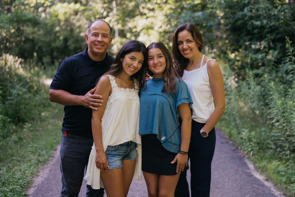 Emma Hollands's dad, sister, and mom posing together on a wooded path