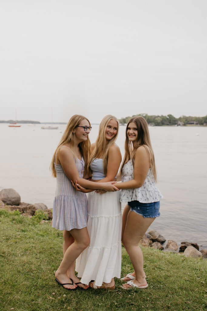full body photo of three senior friends standing together by a Minneapolis lake