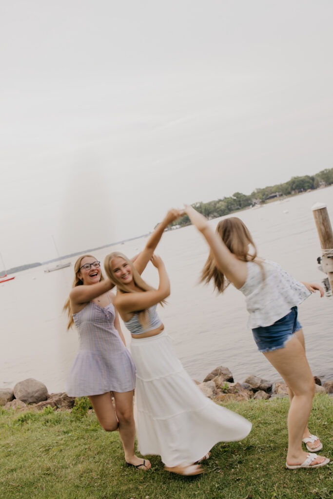 two friends dancing and spinning together on the grass by the lake
