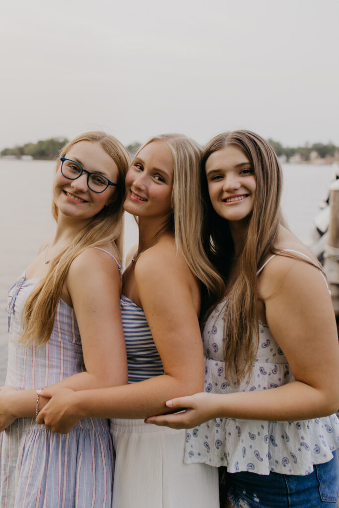 three senior friends standing arm in arm by the lake