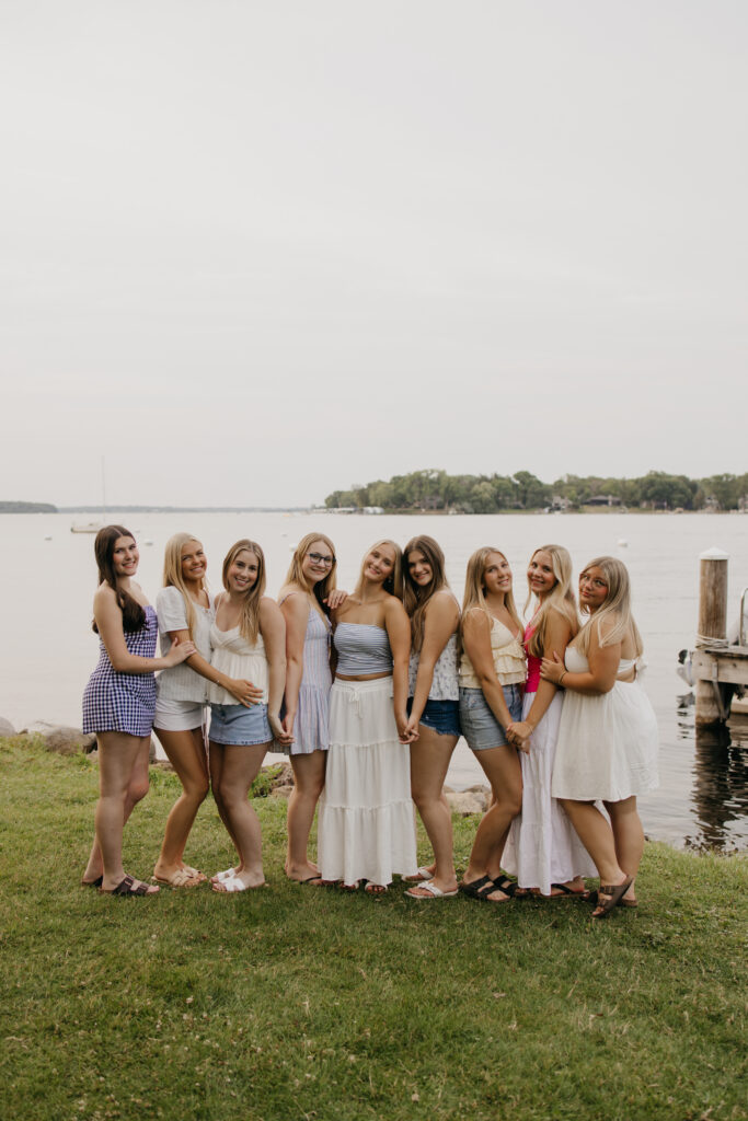 senior friend group photoshoot of friends lined up together near the water