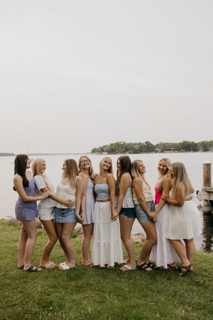 large senior friend group standing together near a lake dock