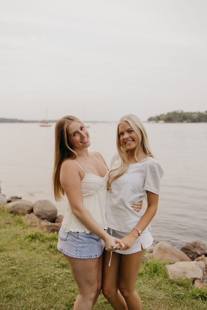 two senior friends smiling at each other by the water