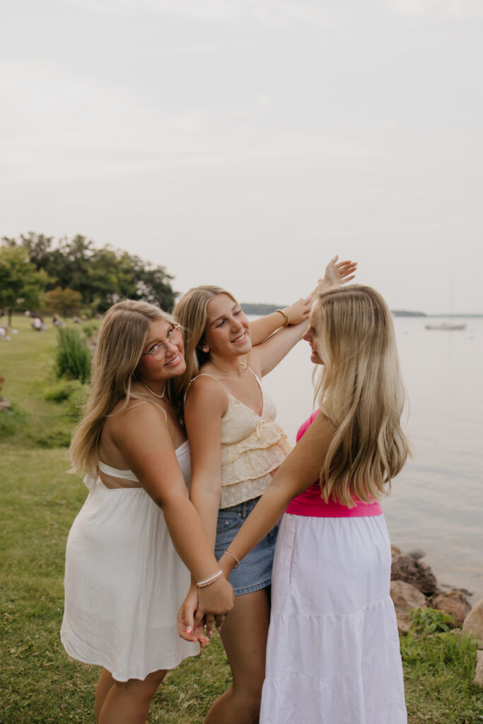 three senior friends laughing together with lake water in the background