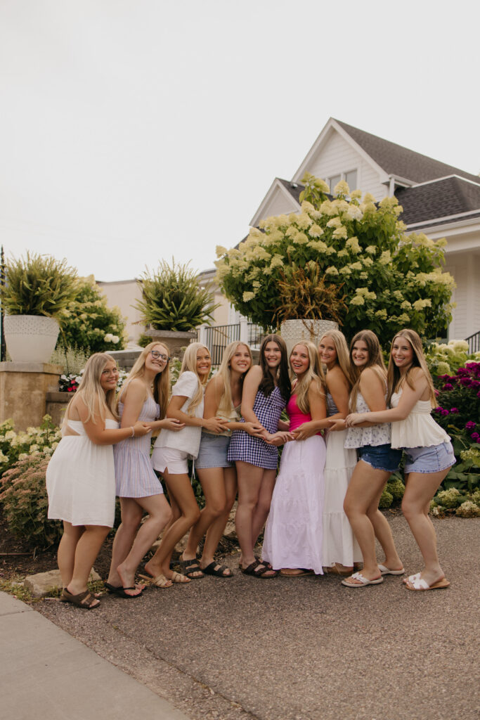 large friend group senior pictures of friends holding hands in a line