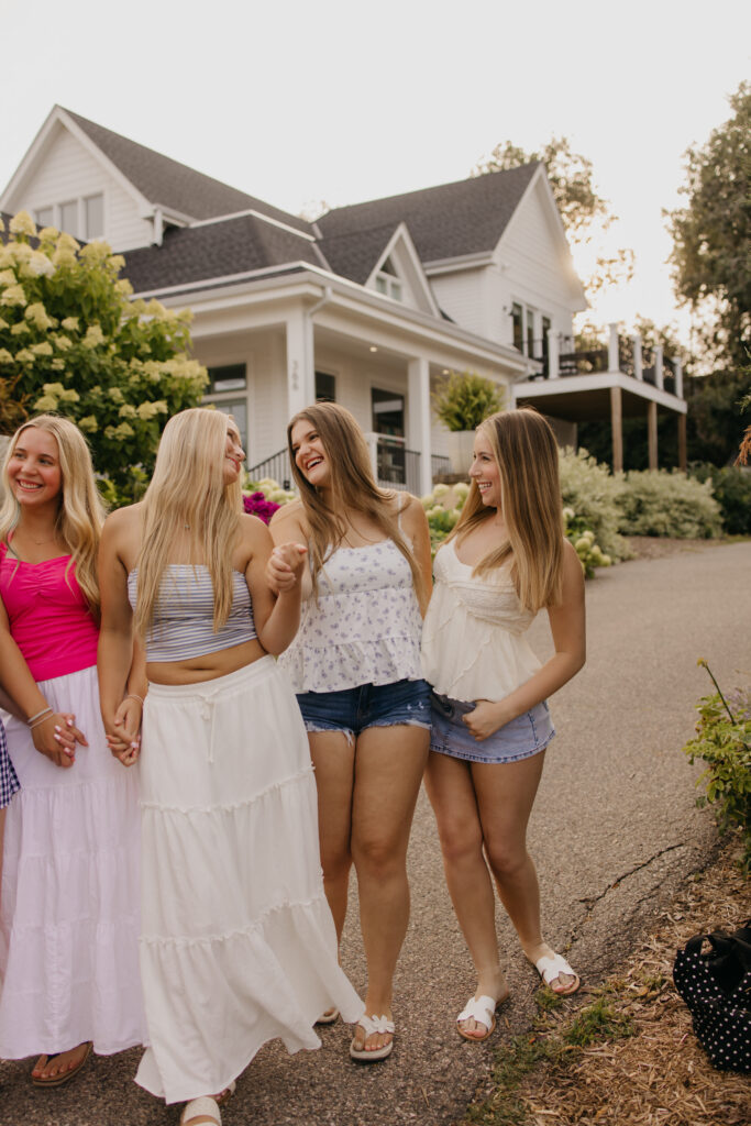 four senior friends laughing together on a driveway