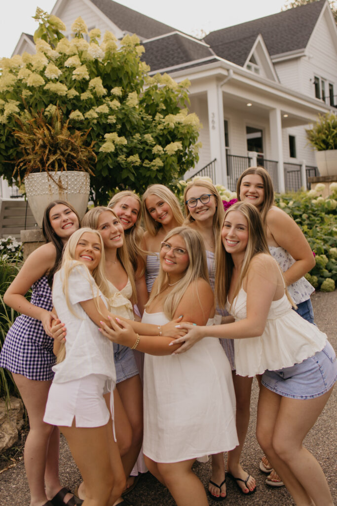 senior photos with friends hugging in a cluster near blooming hydrangeas
