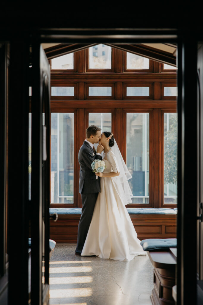Bride and groom kiss in a wood-paneled doorway at the American Swedish Institute in Minneapolis