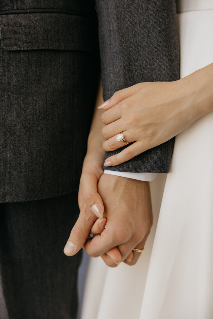 Close-up of the bride and groom holding hands, showing her wedding ring, during their Central Lutheran Church ceremony