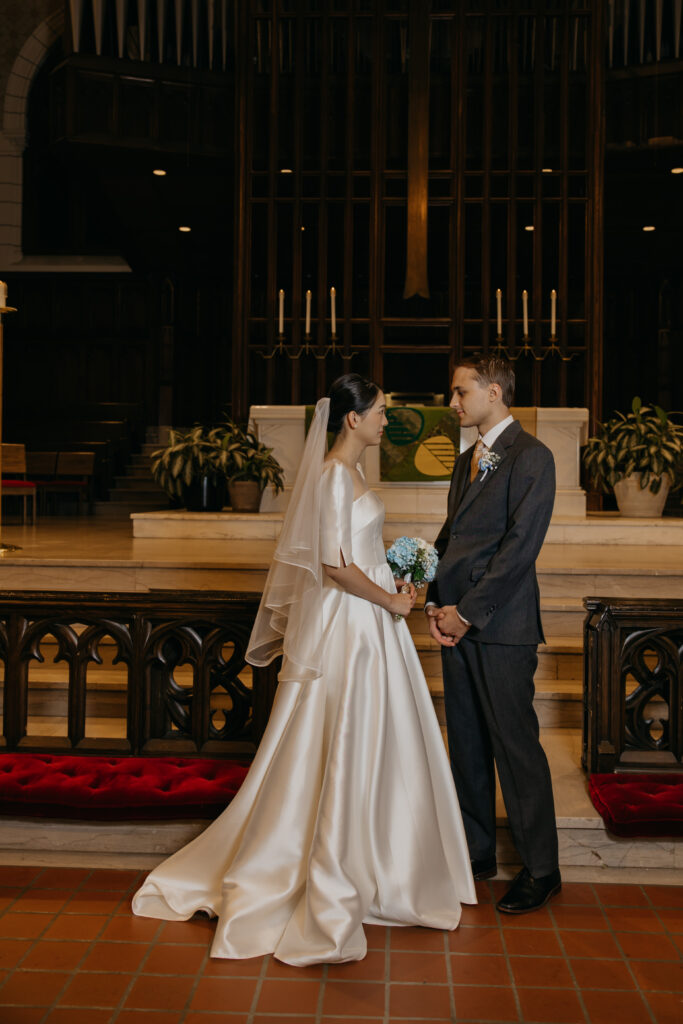 Bride and groom hold hands facing each other at the Central Lutheran Church altar during their vows