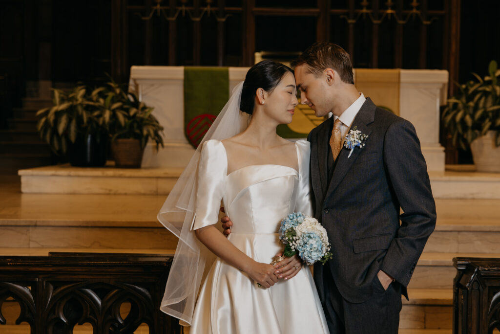 Bride and groom stand together at the altar rail inside Central Lutheran Church, bride holding her bouquet