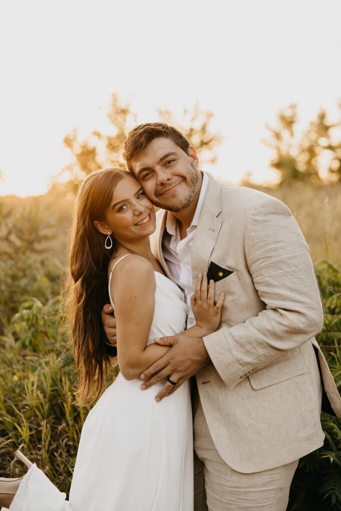 Bride and groom embracing and smiling together in golden hour light