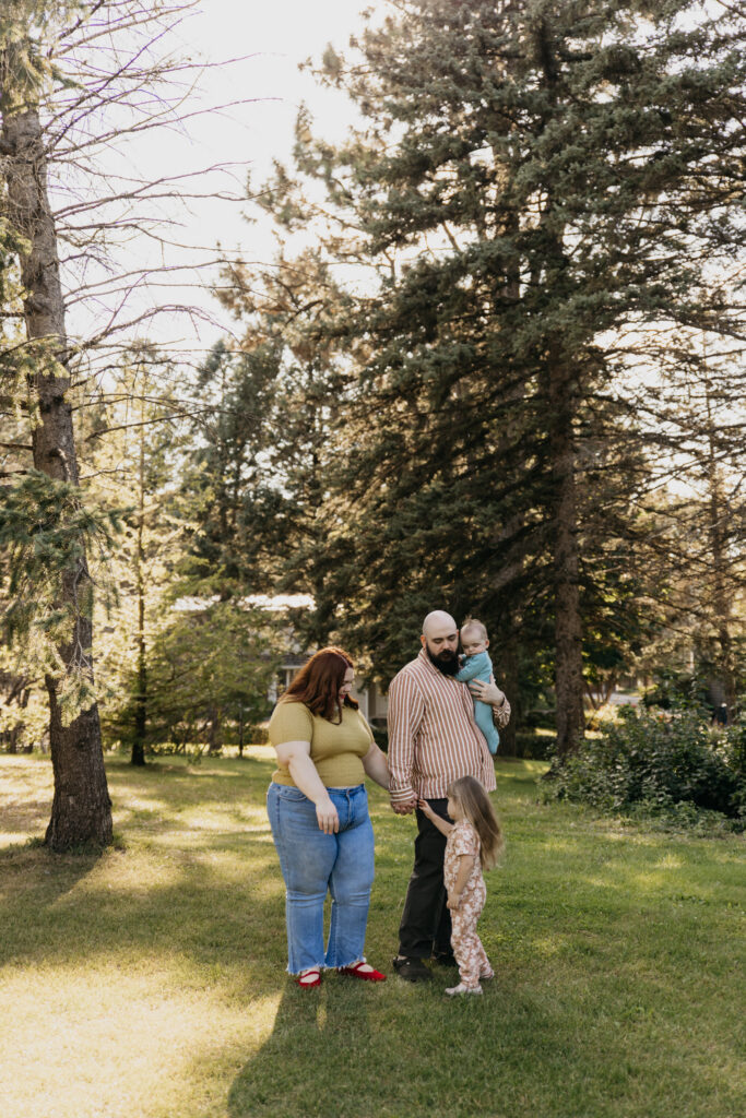 Mom and dad laughing together face to face among tall evergreen trees