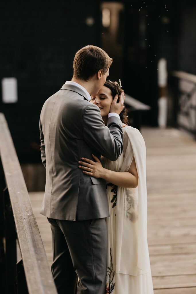 Bride and groom sharing a kiss on a wooden dock at their wedding