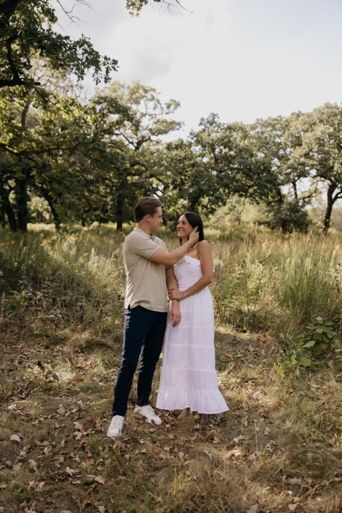 Couple laughing together in an oak-filled Minnesota meadow at golden hour