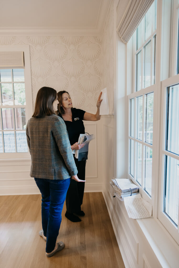 Bumble Bee Blinds consultant measuring a window while a teammate takes notes in a bright room